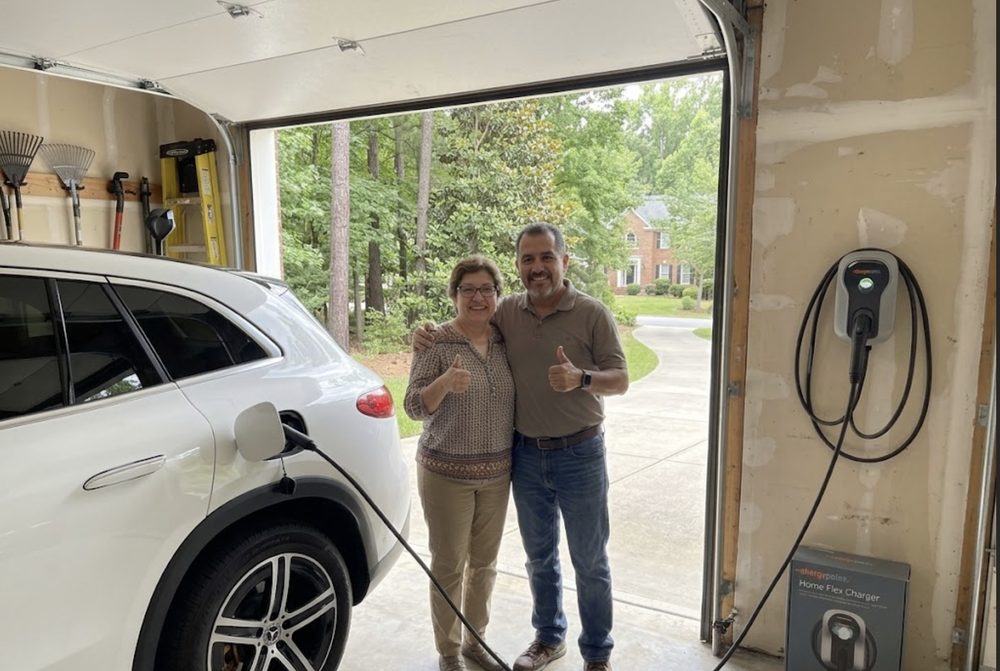 Happy Charlotte homeowners beside their EV charging at home